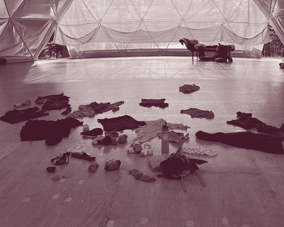 Clothes and socks left in a loose circle on the wooden floor of a dance dome